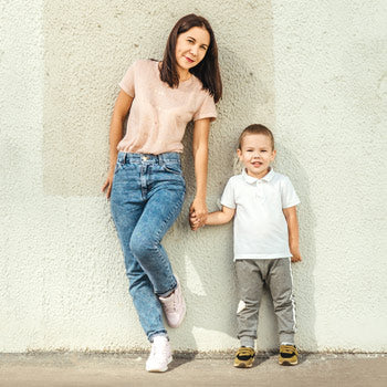 A woman and her child wearing sneakers and holding hands.