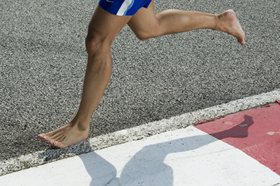 man running barefoot on asphalt